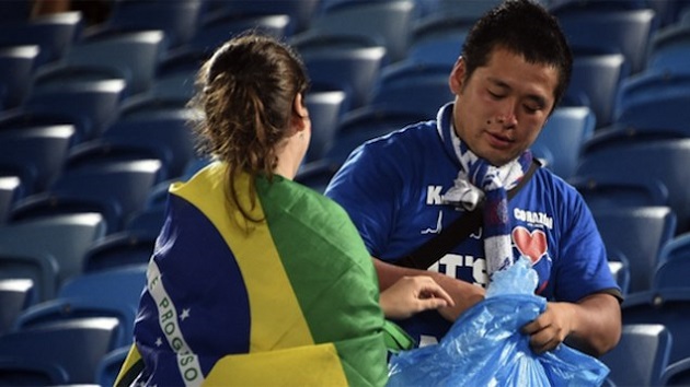 Torcedora brasileira ajuda japonês a recolher o lixo após a partida realizada na Arena das Dunas